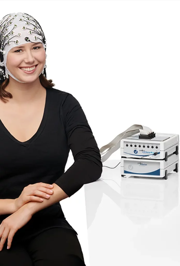 Smiling woman wearing an EEG cap connected to Brain Vision amplifier system