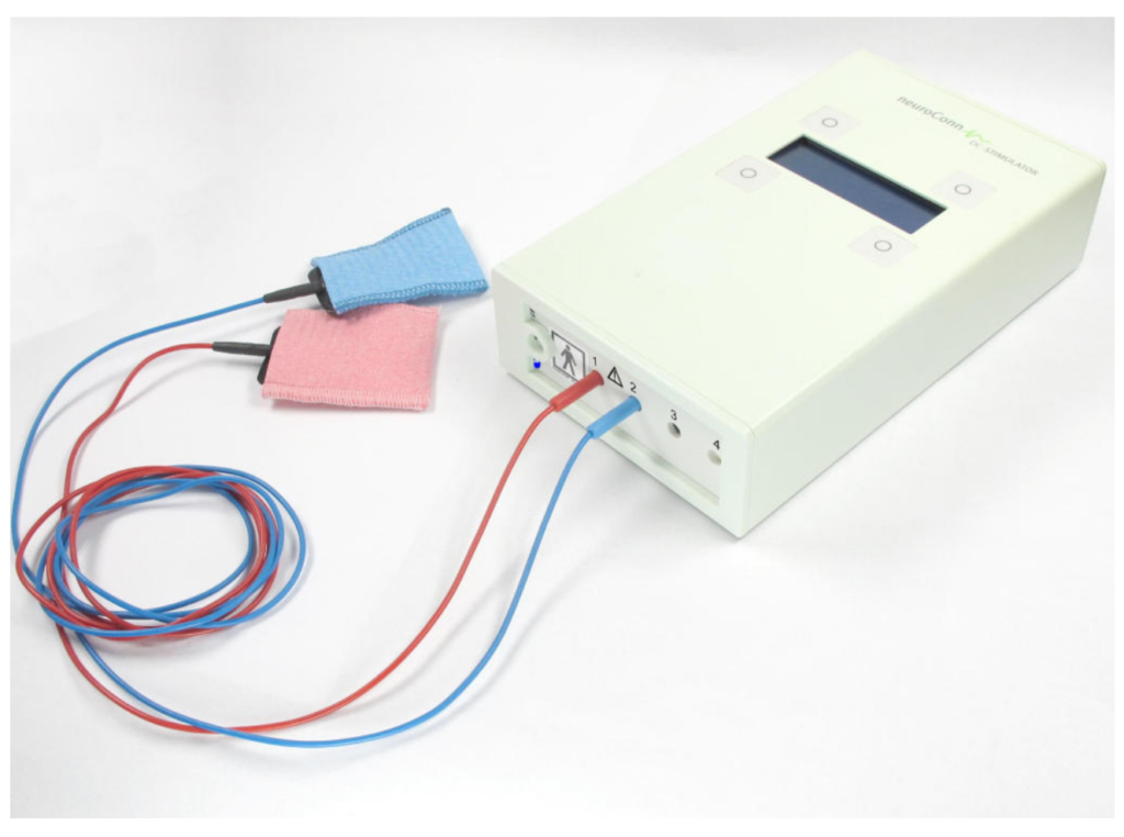 neuroConn DC-STIMULATOR PLUS is depicted laying on a table with a pair of rubber/sponge electrodes connected.