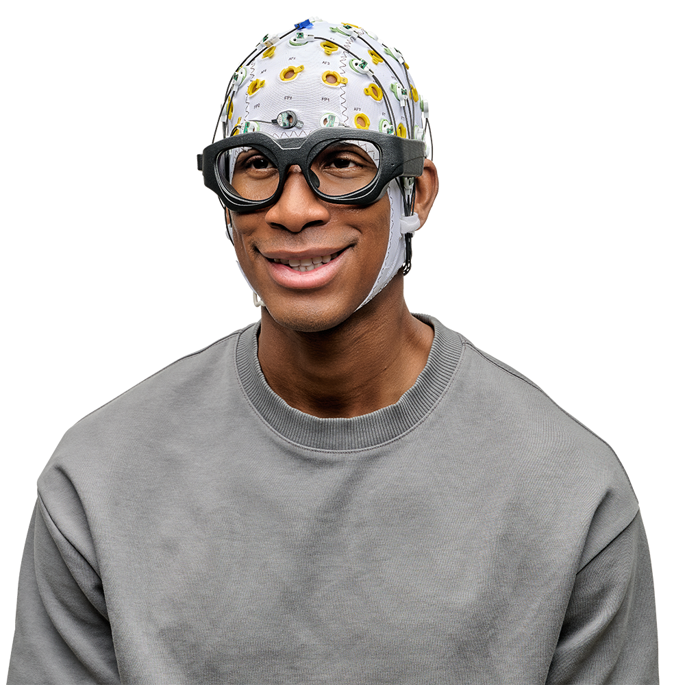 A male participant sits wearable an EEG cap and a set of Emteq OCOsense facial EMG smart glasses.